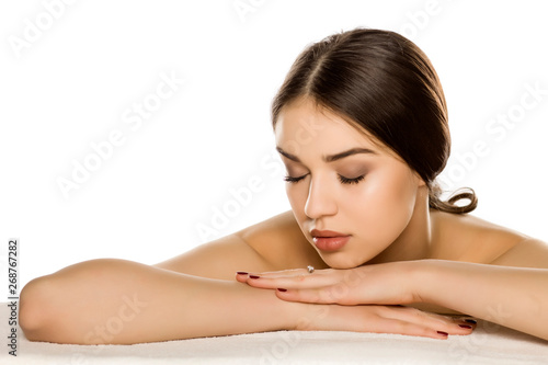 Young woman with makeup lying on white background