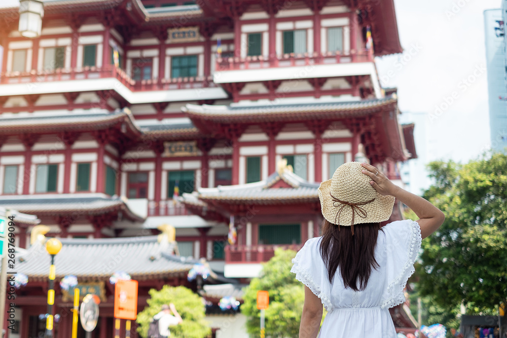 Woman traveling with white dress and hat, Asian traveler looking to Buddha Tooth Relic Temple in Chinatown of Singapore. landmark and popular for tourist attractions. Southeast Asia Travel concept