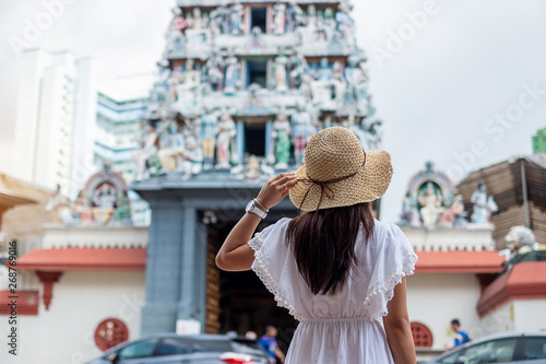 Woman traveling with white dress and hat, happy Asian traveler looking to Sri Mariamman Temple in Chinatown of Singapore. landmark and popular for tourist attractions. Southeast Asia Travel concept
