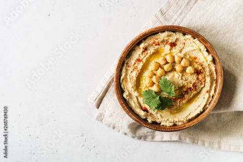 Fotografiet Hummus dip with chickpea, and parsley in wooden plate on white background