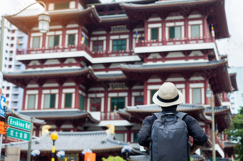 Photography man hipster traveling with backpack and hat, Solo traveler looking to Buddha Tooth Relic Temple in Chinatown of Singapore