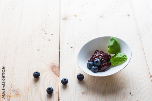 Jam from blueberries in a bowl on a wooden table. For a good delicious breakfast. photo