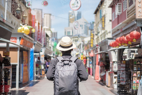Young man hipster traveling with backpack and hat, happy Solo traveler walking at Chinatown street market in Singapore. landmark and popular for tourist attractions. Southeast Asia Travel concept