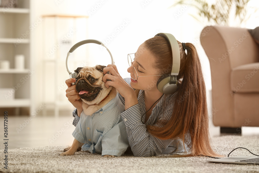 Teenage girl with cute pug dog listening to music at home - obrazy, fototapety, plakaty 