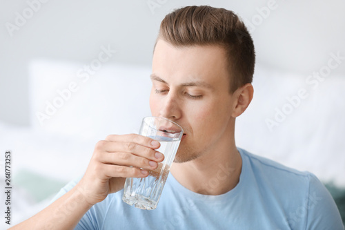 Handsome man drinking water at home