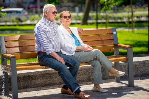 Senior adults walking in a park sitting on a bench talking and smiling