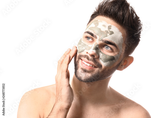 Handsome man with clay mask on his face against white background