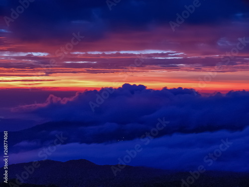 sunrise at Doi Inthanon, mountain view misty morning of the hills around with sea of fog with red sun light and cloudy sky background, KM.41 local of Doi Inthanon National Park, Chiang Mai, Thailand.