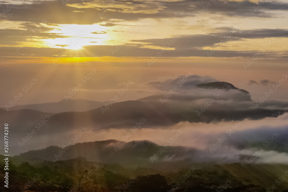 sunrise at Doi Inthanon, mountain view morning of the hills around with sea of fog with sun rays and yellow sky background, KM.41 View Point, Doi Inthanon, Chiang Mai, Thailand.