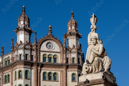 Hungary, Budapest, Ferenciek tere: Front facade of famous Brudern house with two towers, beautiful facade, big clock, statue and blue sky in the city center of the Hungarian capital.