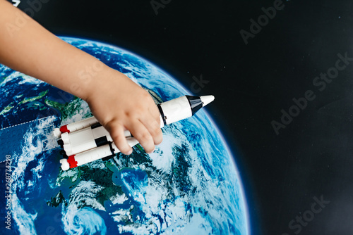 The child's hand plays with the spaceship.