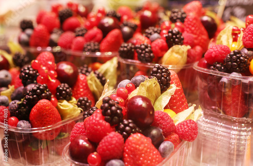 Delicious berries - strawberries  rasberries  grapes  blueberries - in plastic packaging sold at Barcelona s oldest and most famous food market La Bokheria. Spain. 