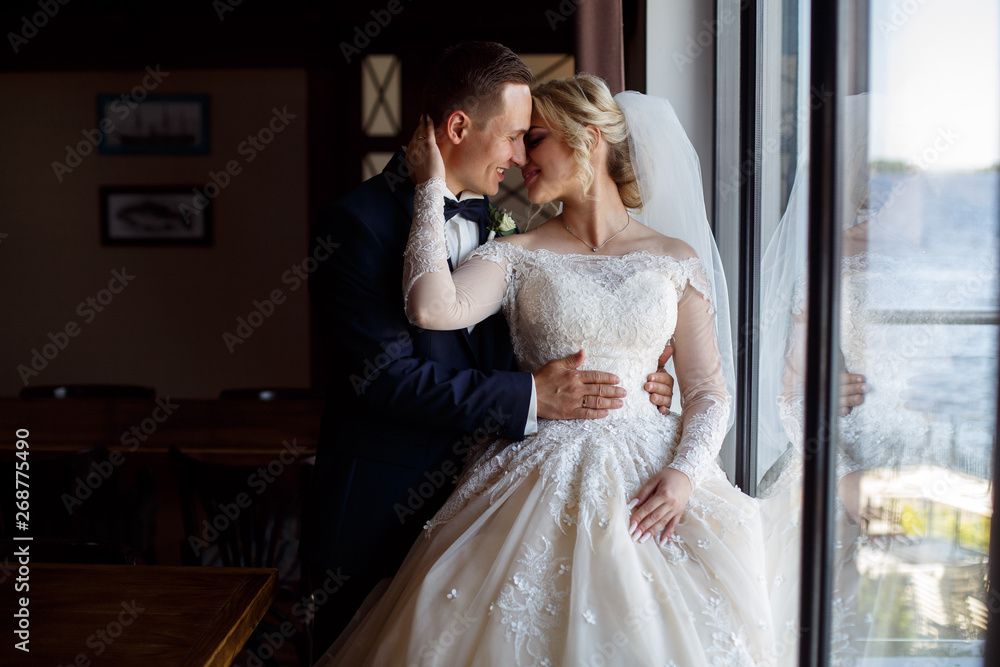 portrait of emotional lovers of brides indoor.Bride and groom kisses tenderly . emotional  photo of a couple in love on the wedding day.smiling newlyweds. Wedding photography. 