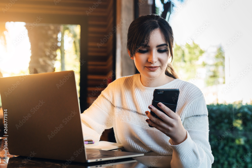 Girl browsing social networks on smartphone while sitting cafe. Blogger chatting with followers oncell phone coffee shop.Lifestyle Girl browsing social networks on smartphone while sitting cafe. Blogger chatting with followers oncell phone coffee shop.Lifestyle