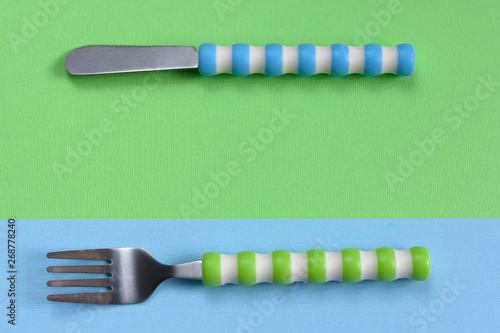 children tableware ( knife, fork) set on green blue background