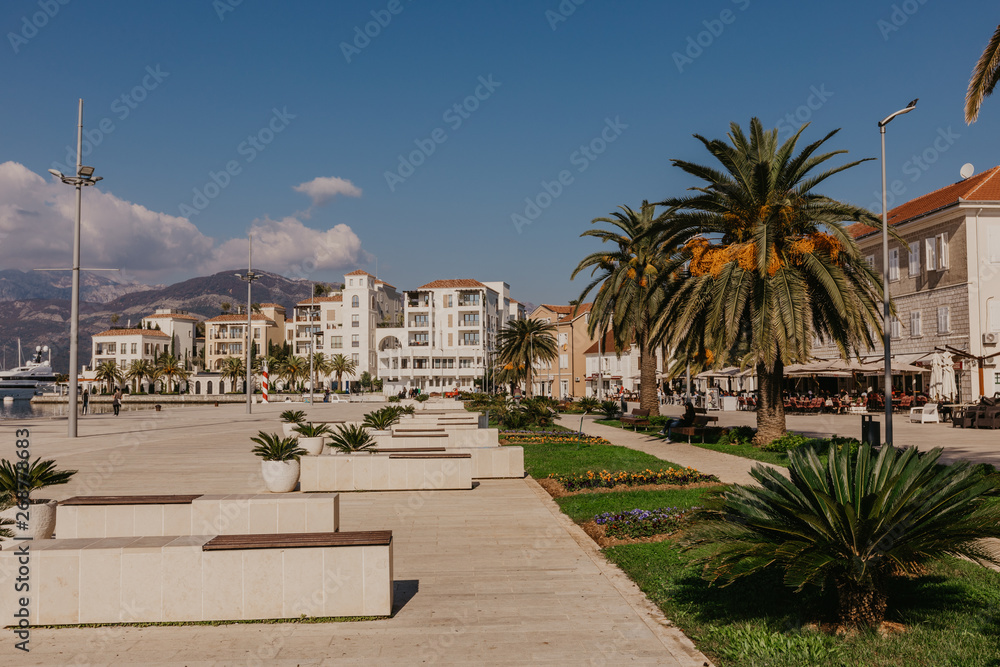 TIVAT, MONTENEGRO - NOVEMBER 9, 2018: Tourists walking on sunny seafront of Tivat city.
