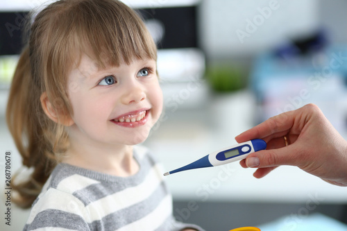 Female hand holding thermometer measuring sick little girl closeup