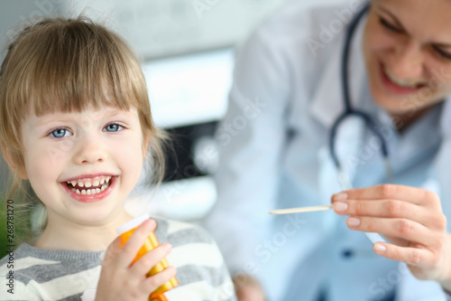 Cute smiling happy little girl hold in hand bottle of tablets at doctor office portrait