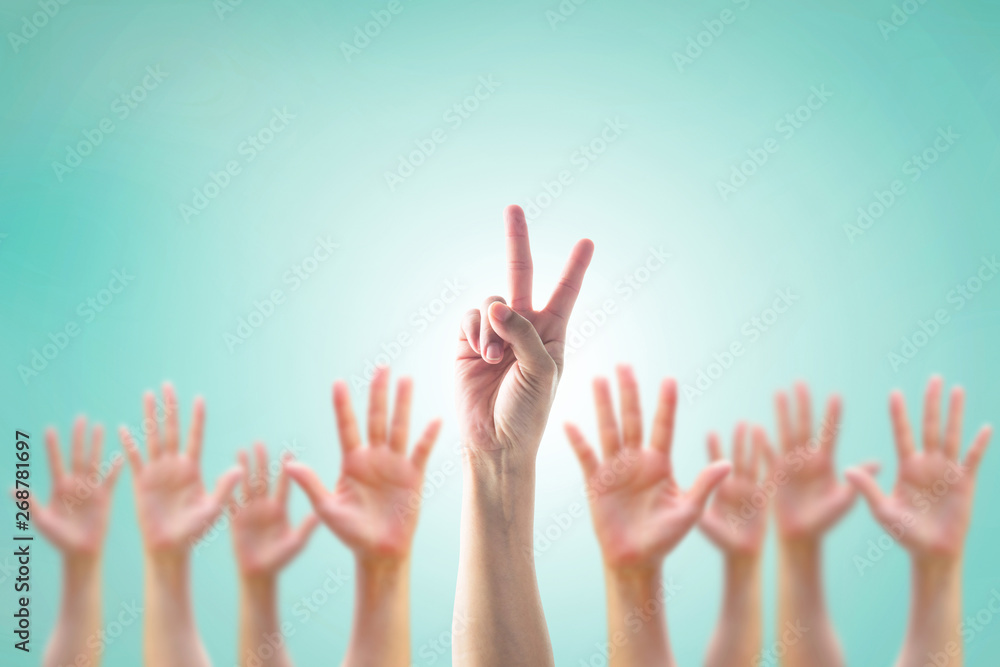 Leader's two fingers victory sign among blur hands crowd group for World participation, leadership, volunteer concept