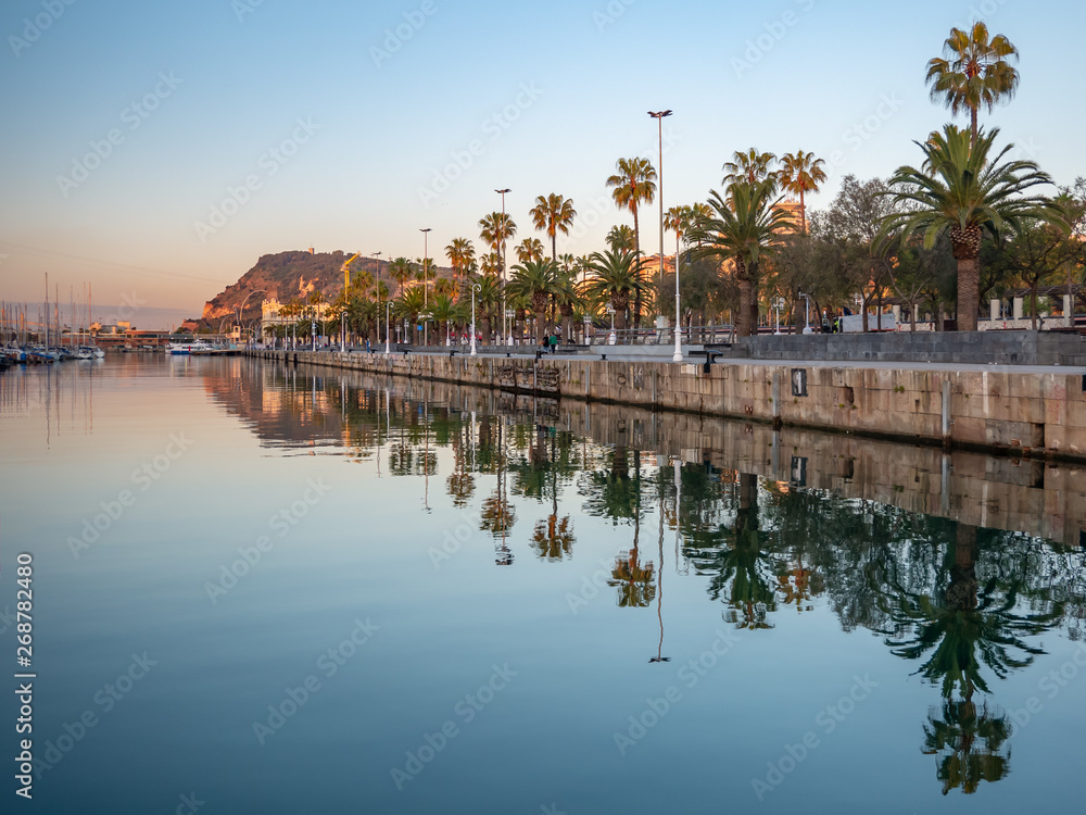 View of a promenade passing Port Vell in Barcelona during the sunrise.