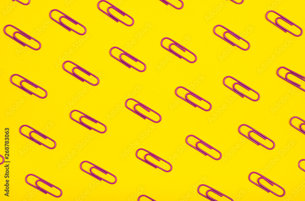 Violet paper clips pattern on yellow background.