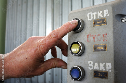 Finger of worker pushing button Open on a control panel of pumping station