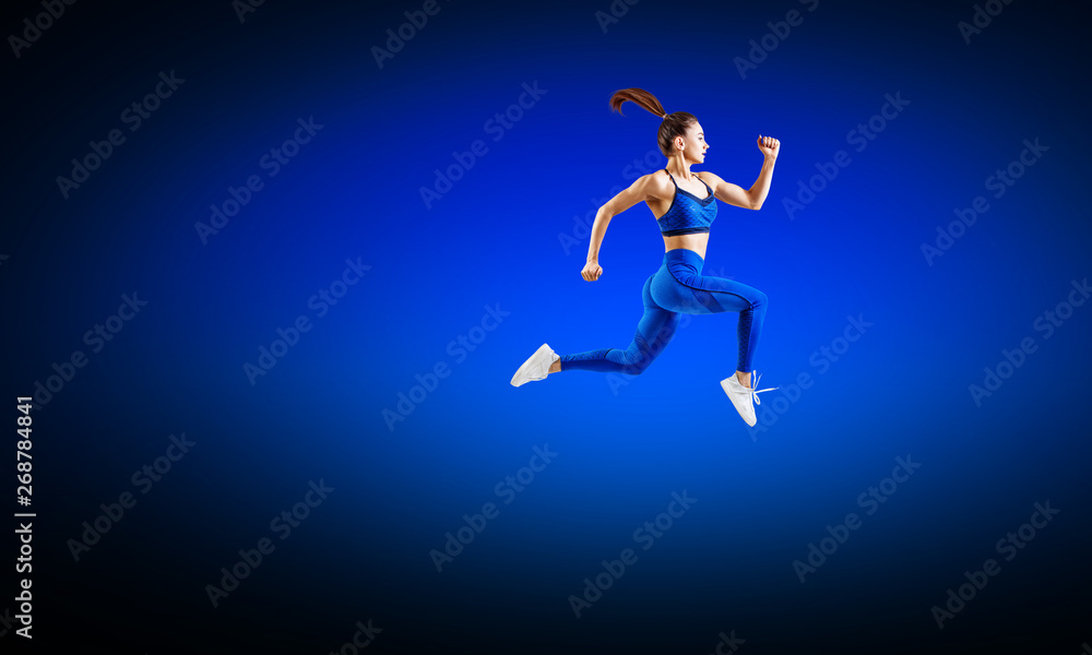 Young woman runner in blue sportswear jump in the air.