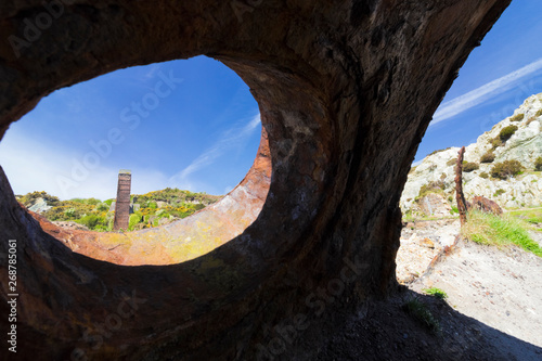 Vista from a rusted old boiler drum on the disused Porth Wen Brickworks looking back towards a brick chimney  Anglesey  North Wales