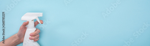 panoramic shot of woman holding white spray bottle with detergent on blue background