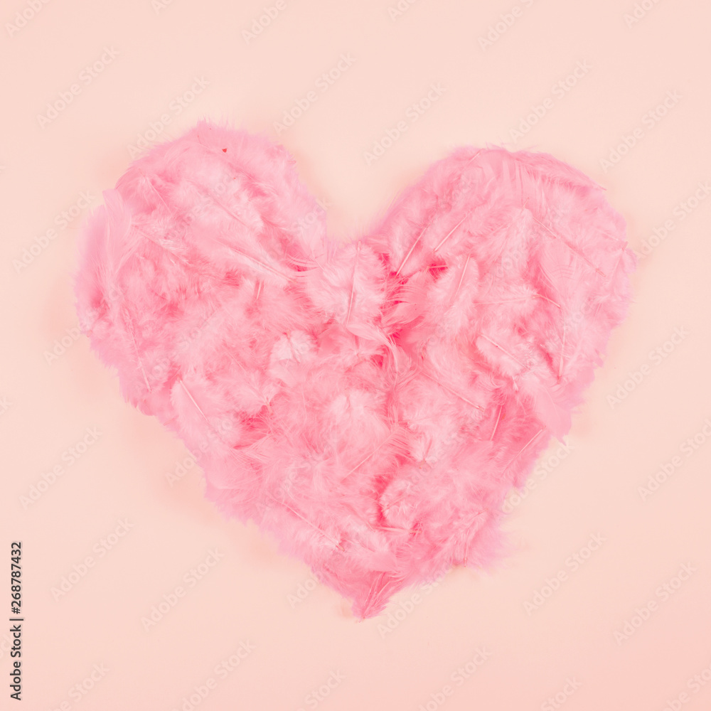 Pink soft feather heart shape on peach colored background