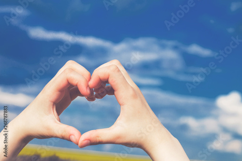 child  heart from hands on a background of blue sky