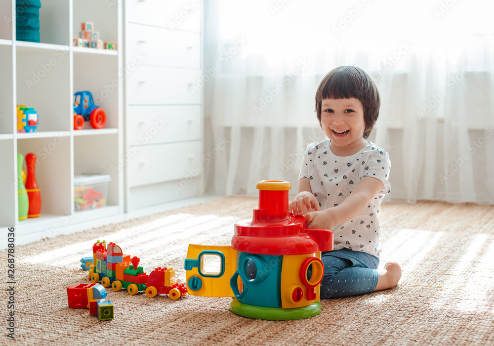 Child playing with colorful toy blocks on the floor in the room Educational toys for young children. Sorter for baby or toddler Child playing with colorful toy blocks on the floor in the room Educational toys for young children. Sorter for baby or toddler