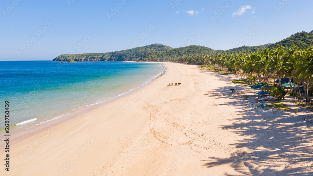 Wide tropical beach with white sand and small islands, top view. Nacpan Beach El Nido, Palawan. Seascape in clear weather, view from above. Wide tropical beach with white sand and small islands, top view. Nacpan Beach El Nido, Palawan. Seascape in clear weather, view from above.
