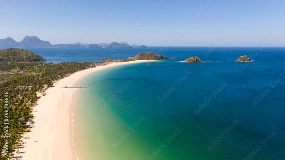 Fototapeta premium Wide tropical beach with white sand and small islands, top view. Nacpan Beach El Nido, Palawan. Seascape in clear weather, view from above.