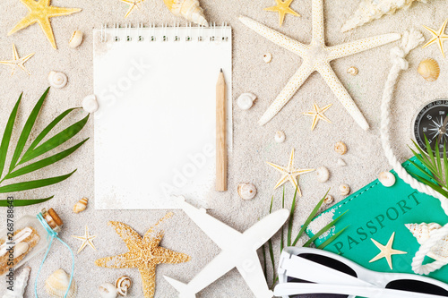 Empty notebook with accessories for planning summer holidays, travel and vacation on sand background top view. Flat lay style.