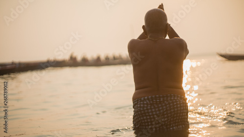 Cuadro en lienzo Old Hindu man praying and bathing in Ganges River during sunrise in Varanasi, In
