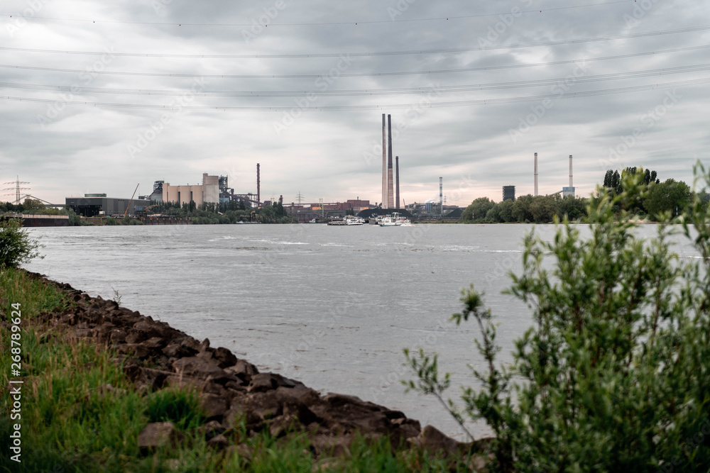 Obraz premium NRW/GERMANY - MAY 16, 2019: View of the industrial area with production plants next to the river rhine in Duisburg, Germany.