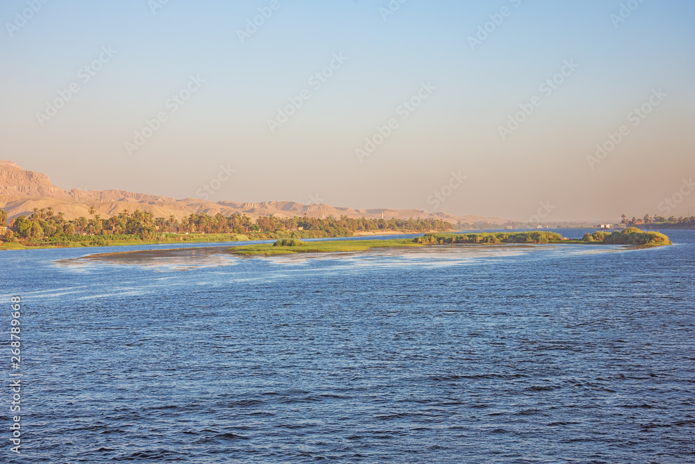 A island in the Nile with distant cruise ships passing Ezbet El-Gawad