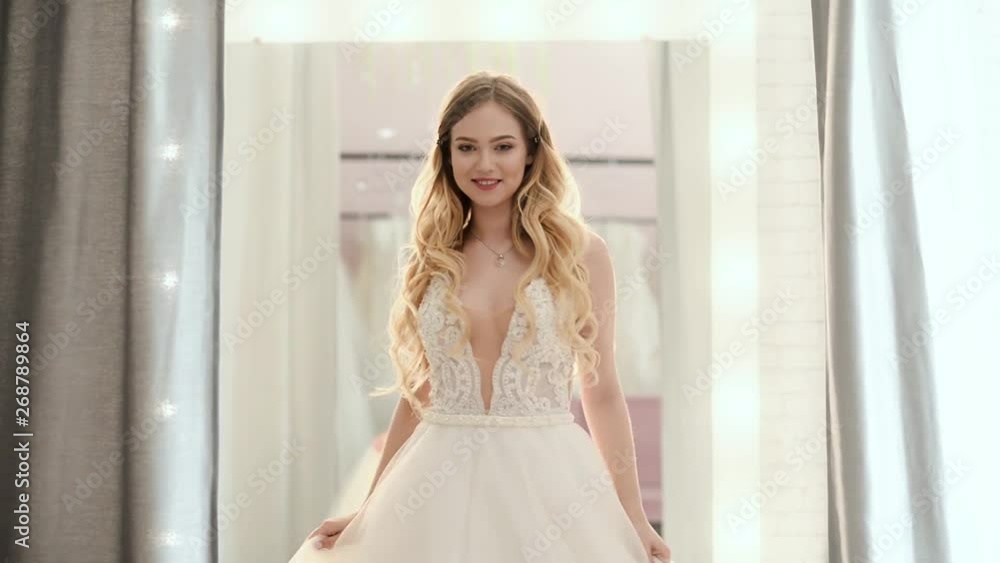 beautiful blonde curly girl in wedding salon is wearing a dress near loft mirror beautiful blonde curly girl in wedding salon is wearing a dress near loft mirror