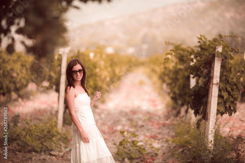 Smiling woman in white dress standing in vineyard