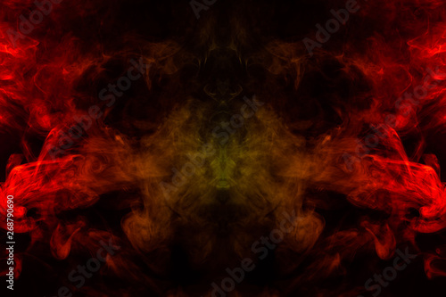 Smoke of different orange and red colors in the form of horror in the shape of the head, face and eye with wings on a black isolated background. Soul and ghost in mystical symbol of bat