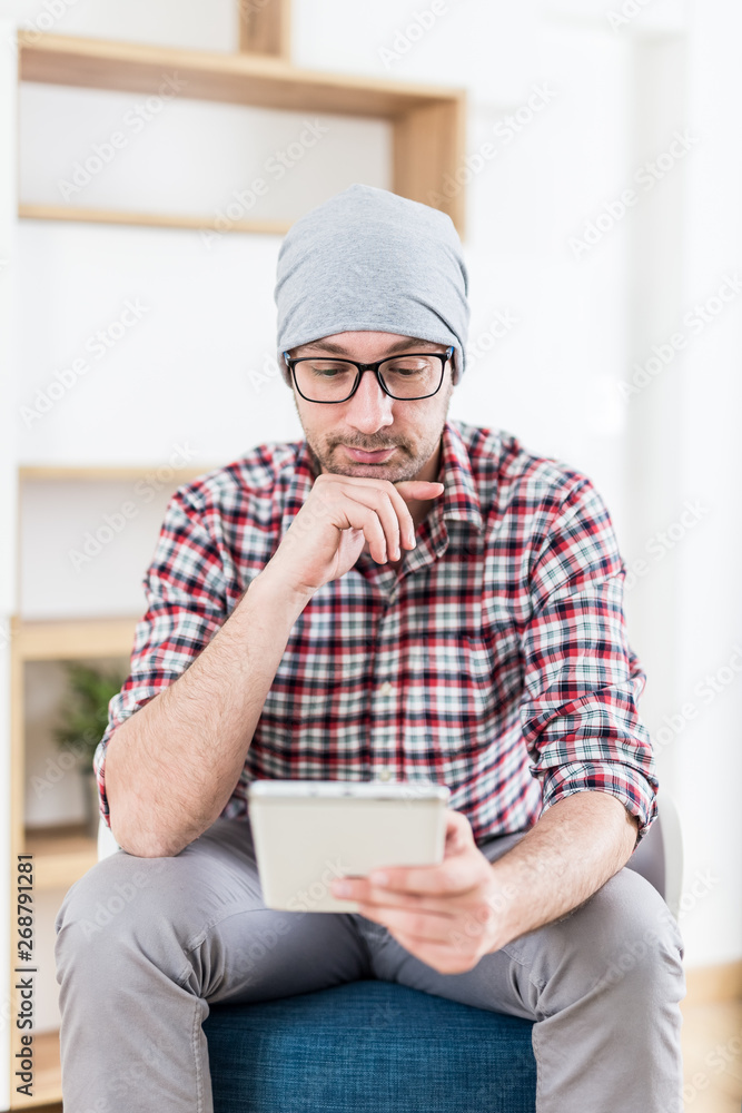 Portrait of young hipster businessman sitting at the office and using digital tablet. Portrait of young hipster businessman sitting at the office and using digital tablet.