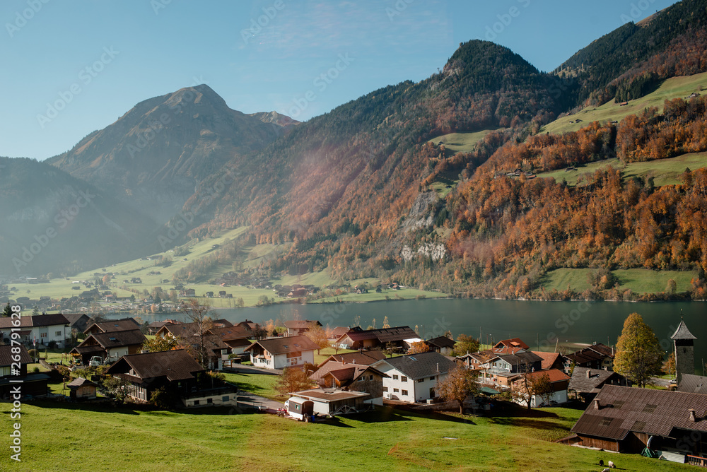 Scenic view from the train to the valley in Switzerland. Small town and lake among town in Switzerland. Adventure in journey. Beautiful nature in autumn. Sunny day. Travel to Europe