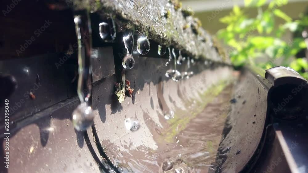 Water dripping from the gutter in slow motion. Drops of crystal clear