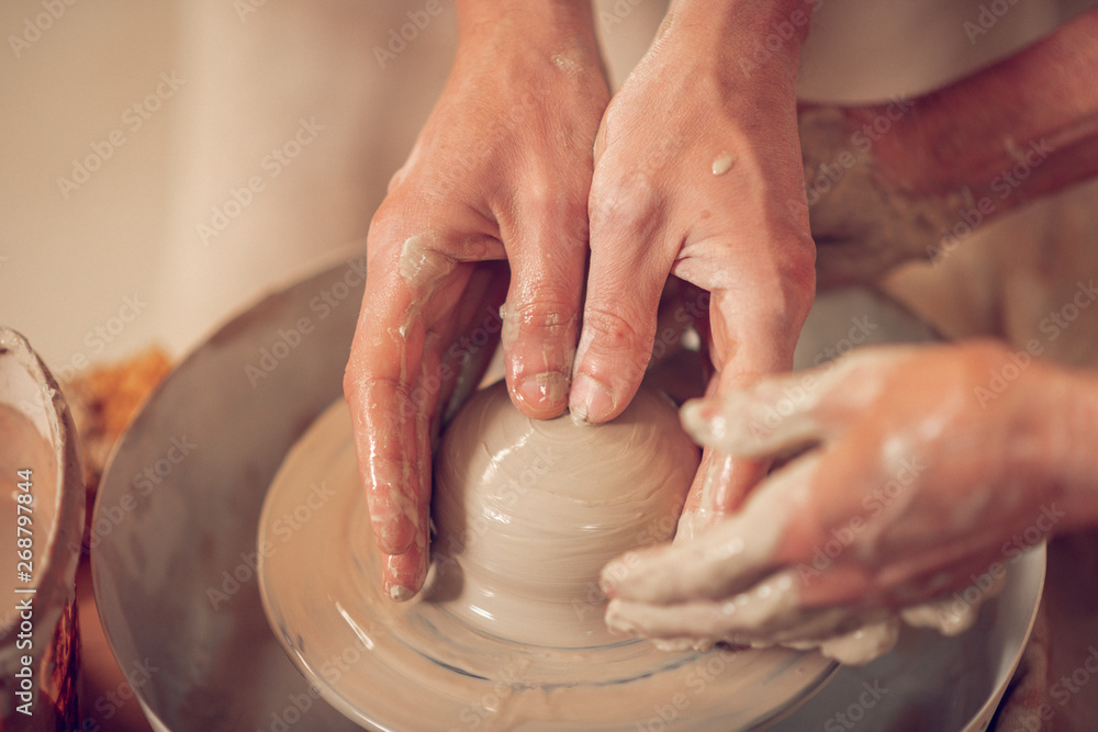 Close up of female hands touching the pottery wheel
