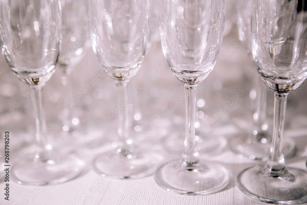 many empty champagne glasses close up. glass goblets on the white table. Empty crystal wineglass. glass goblet on a high leg. many empty champagne glasses close up. glass goblets on the white table. Empty crystal wineglass. glass goblet on a high leg.