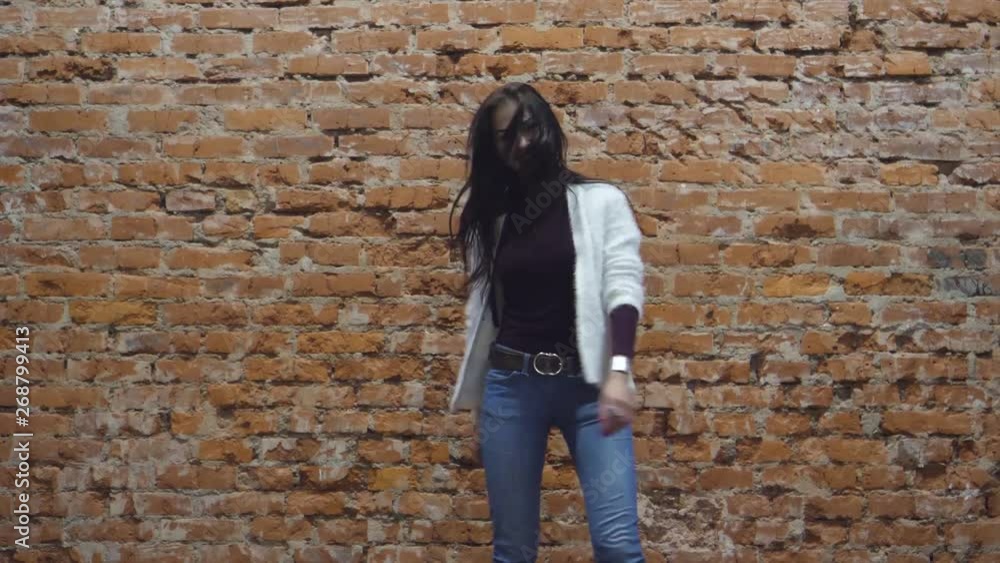 girl near a brick wall shows clothes and smiles girl near a brick wall shows clothes and smiles