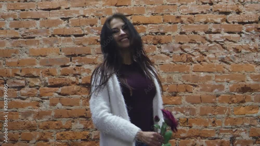 girl near a brick wall shows clothes and smiles girl near a brick wall shows clothes and smiles