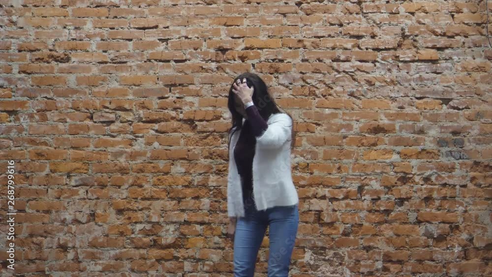 girl near a brick wall shows clothes and smiles girl near a brick wall shows clothes and smiles