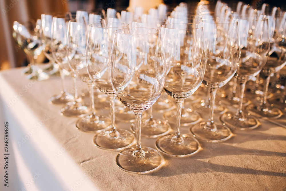 many empty champagne glasses close up. glass goblets on the white table. Empty crystal wine glass. glass goblet on a high leg. many empty champagne glasses close up. glass goblets on the white table. Empty crystal wine glass. glass goblet on a high leg.